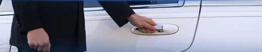 A hand opening the door of a white limousine