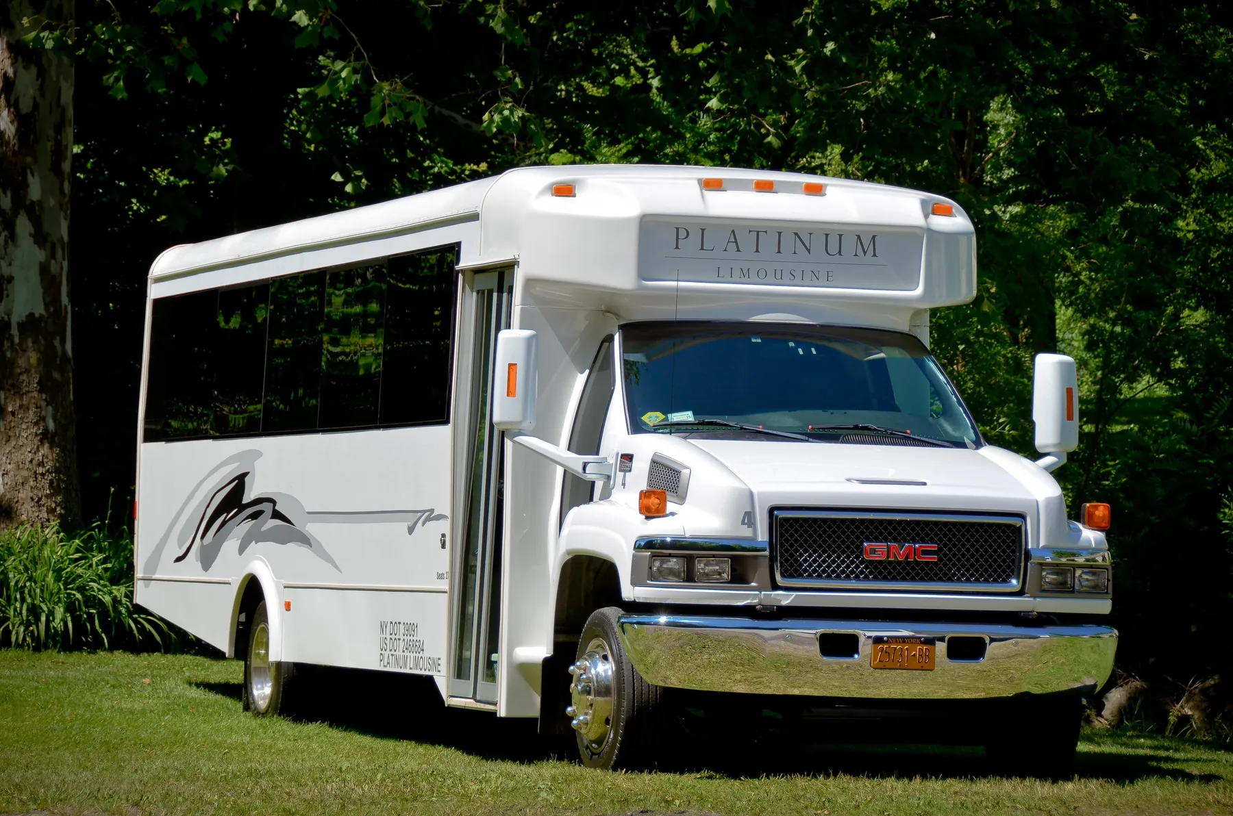 The white Platinum Limousine 27 passenger coach parked on a lawn