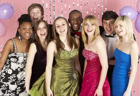 A group of prom-goers in formal wear laughing together