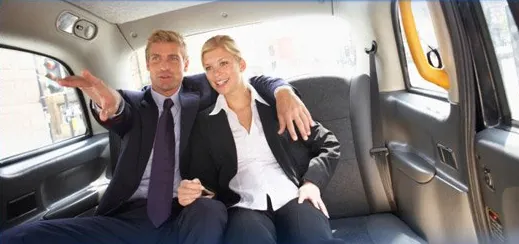 Two business travellers relaxing in the back of a limousine