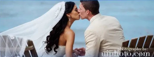 A bride and groom kissing by the water